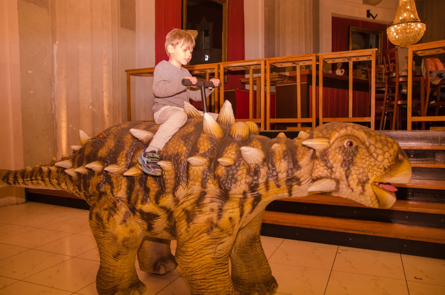 Die lebendige Dinosaurier Show, ein Kind reitet auf einem Dinosaurier-Rücken